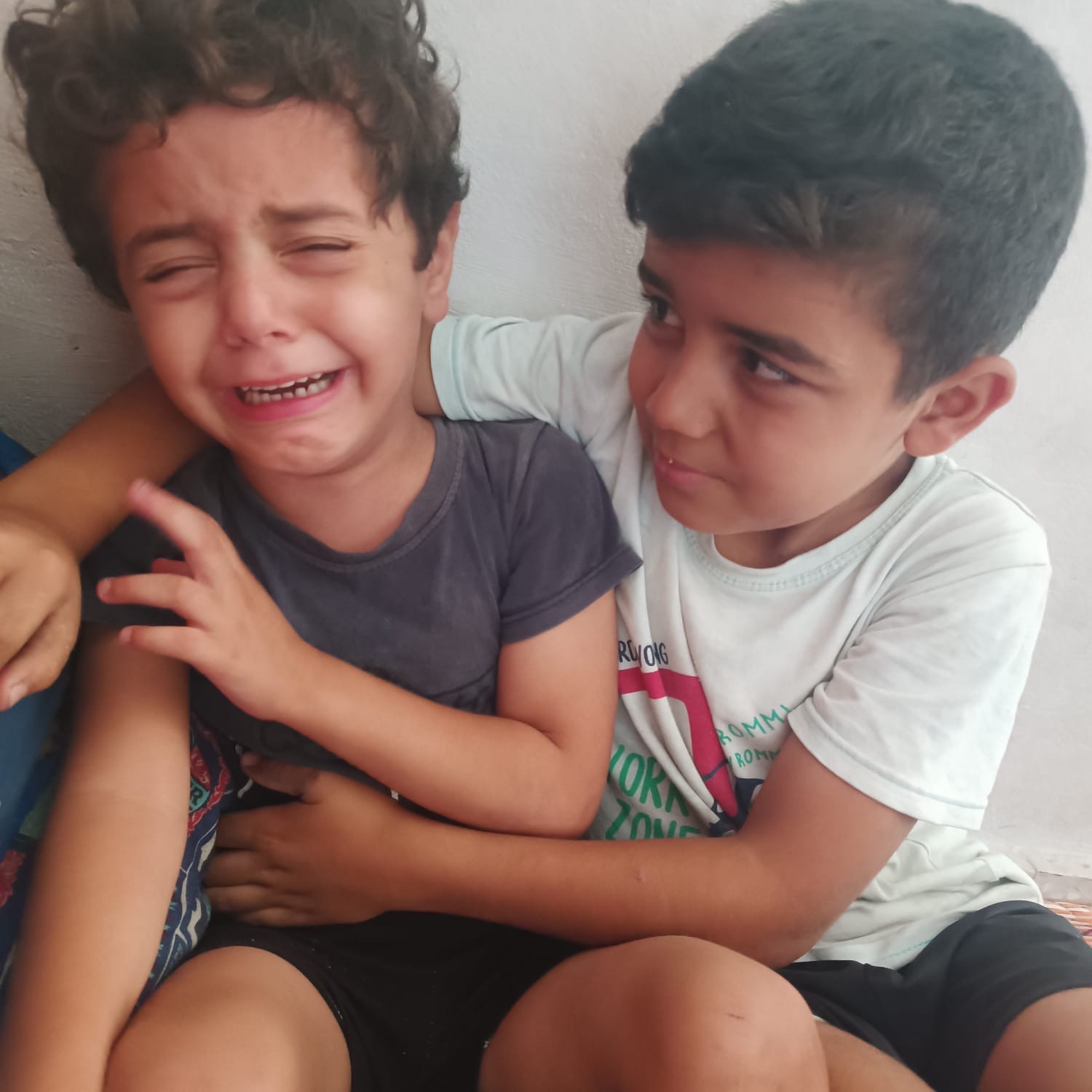 Jude crying while Musa comforts him in Gaza shelter; Help Gaza family evacuate.