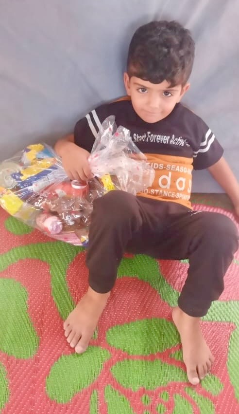 Boy sitting with snacks provided by volunteers in Gaza; Gaza child medical aid.